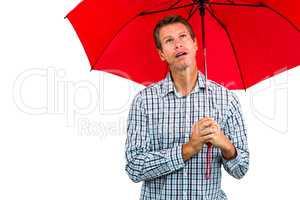 Thoughtful man looking up while holding red umbrella