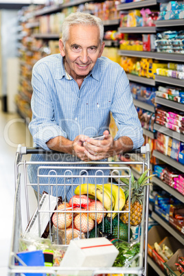 Senior man using phone at grocery store