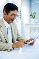 Smiling asian businessman using tablet