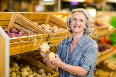 Smiling senior woman holding potatoes