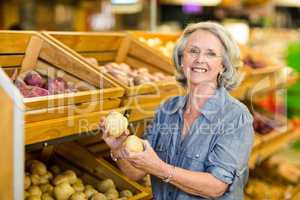 Smiling senior woman holding potatoes