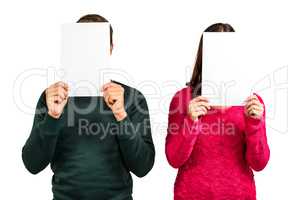 Couple hiding faces with documents