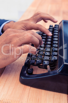 Businessman typing on typewriter at wooden desk