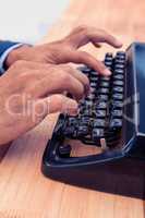 Businessman typing on typewriter at wooden desk