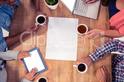 Professionals using technologies while holding coffee cups