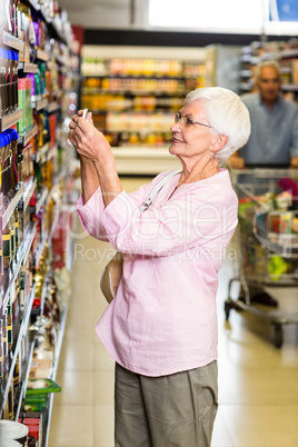 Senior woman taking a picture of product on shelf