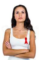 Serious woman with arms crossed with red ribbon on shirt