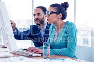 Serious businessman and businesswoman discussing over computer