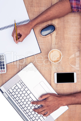 Overhead view of businessman working on laptop while writing on