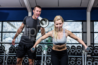 Male trainer motivating fit woman with megaphone