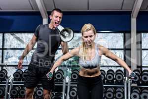 Male trainer motivating fit woman with megaphone