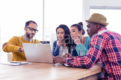 Serious businessman with colleagues discussing on laptop