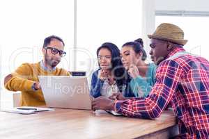 Serious businessman with colleagues discussing on laptop