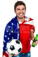 Smiling man holding football and beer bottle wearing American fl