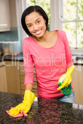 Smiling brunette cleaning kitchen counter