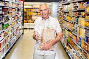 Senior man with grocery bag using smartphone