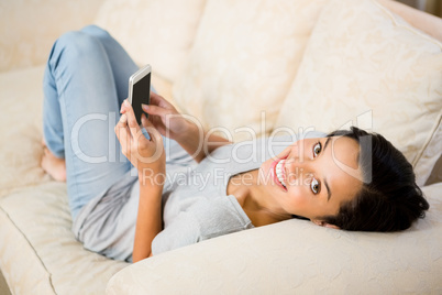 Smiling brunette using smartphone