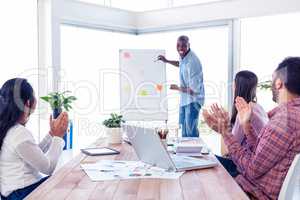 Cheerful businessman giving presentation while team applauding i