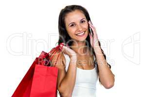Smiling woman holding shopping bags while using smartphone