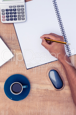 Directly above shot of businessman writing on notebook by coffee