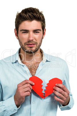 Sad man holding heart halves