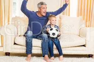 Father and son exulting on the sofa