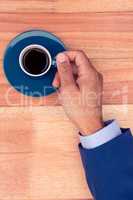 High angle view of businessman holding coffee cup at desk