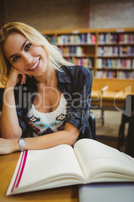 Smiling student reading a book at table