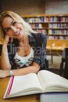 Smiling student reading a book at table