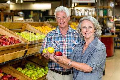 Smiling senior couple holding apples