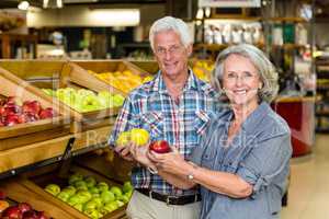 Smiling senior couple holding apples