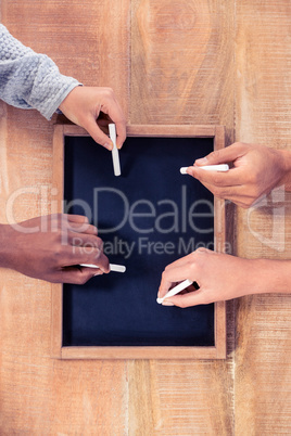 Cropped hands of business people writing on slate