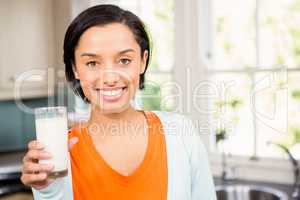 Happy brunette holding glass of milk