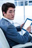 Serious asian businessman using his tablet