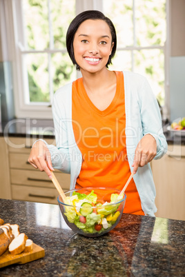 Smiling brunette preparing salad