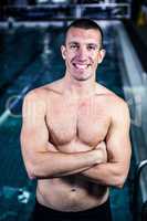 Smiling muscular swimmer with arms crossed