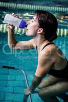 Woman cycling in the pool while drinking water