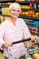 Smiling senior woman pushing trolley