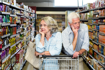 Thoughtful senior couple with cart