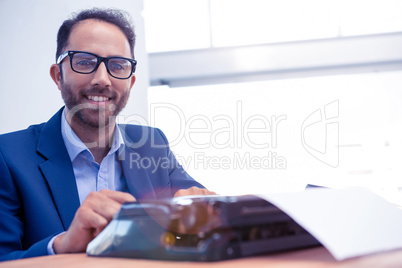 Portrait of happy businessman working on typewriter