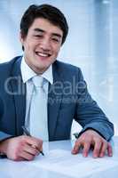 Smiling asian businessman signing a contract