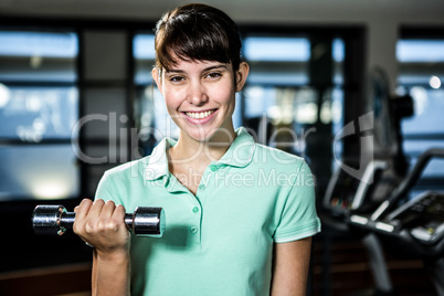 Smiling fit woman doing dumbbells exercise