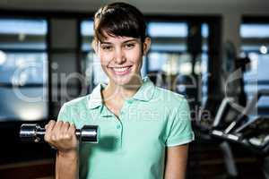 Smiling fit woman doing dumbbells exercise