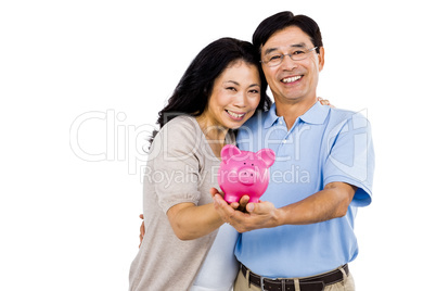 Happy couple holding a piggy bank