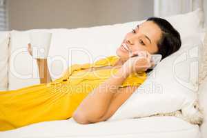 Smiling brunette on a phone call holding cup