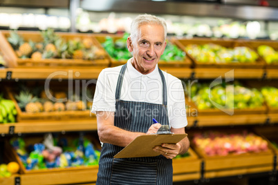 Mature worker writing on clipboard