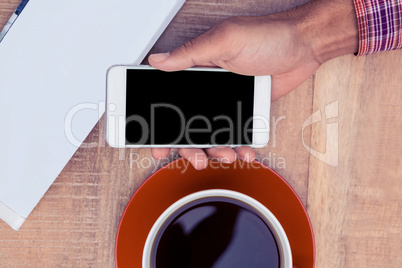 Person using smart phone on desk by coffee