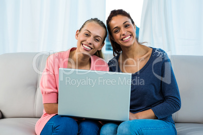 Friends using laptop on sofa