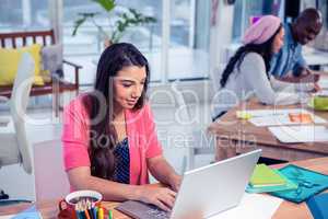 Businesswoman using laptop while working with colleagues