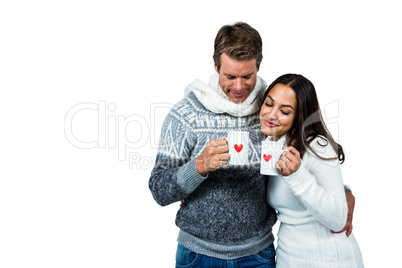 Festive couple smiling and holding mugs